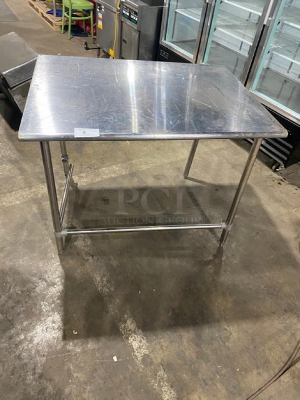 Commercial stainless steel open base worktop table with legs, lightly scratched surface, ideal for kitchen use.