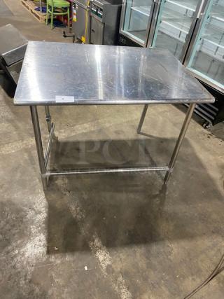Commercial stainless steel open base worktop table with legs, lightly scratched surface, ideal for kitchen use.
