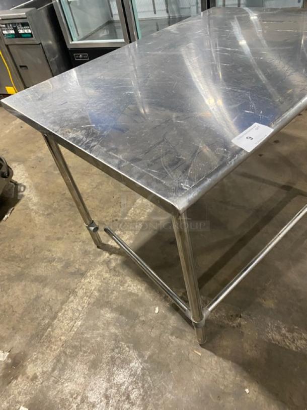 Commercial stainless steel open base worktop table with legs. Minor surface scratches; sturdy industrial design; ideal for kitchens.