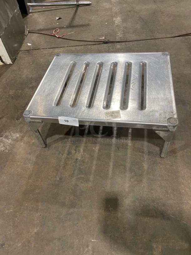 Commercial stainless steel dunnage rack with slotted top and sturdy legs, in good condition.