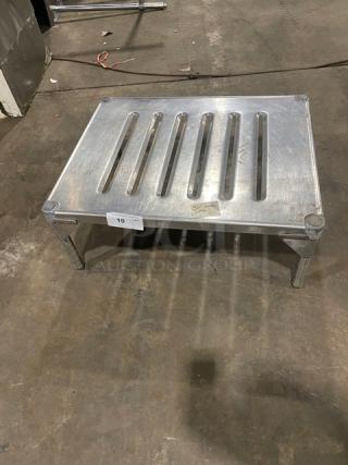 Commercial stainless steel dunnage rack with slotted top and sturdy legs, in good condition.