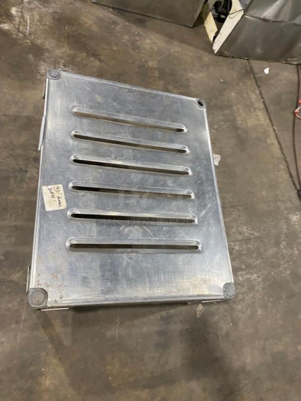 Commercial stainless steel dunnage rack with legs. Features slotted top for ventilation. Used condition, visible surface wear.