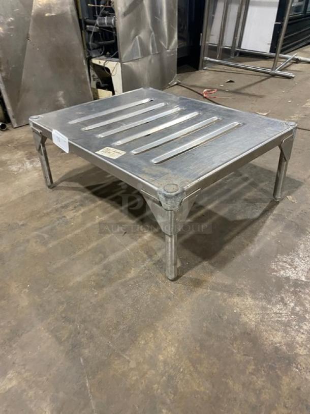 Commercial stainless steel dunnage rack, square with slotted top, durable legs, excellent condition, ideal for storage.