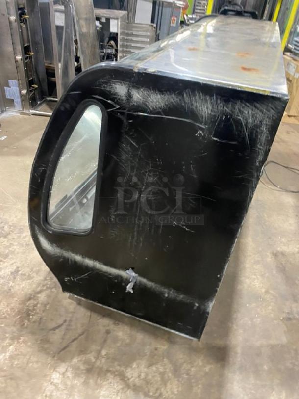 Tor-Rey TEM-200NG commercial black refrigerated display case, curved glass, rear double sliding door, scratched exterior.