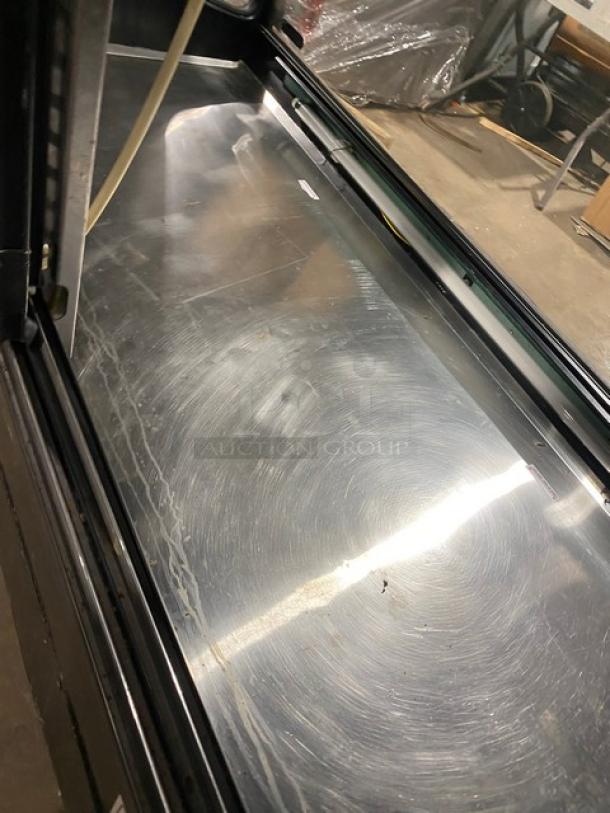 Tor-Rey TEM200NG black curved glass refrigerated bakery merchandiser with rear double glass sliding door, model TEM-200NG, SN: H09-0360, 127V, showing interior surface condition.