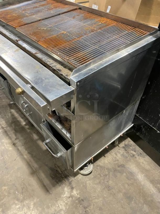 Commercial stainless steel Chitwood smoker/char broiler grill, natural gas/charcoal powered, with pan slide, enclosed storage, on casters.