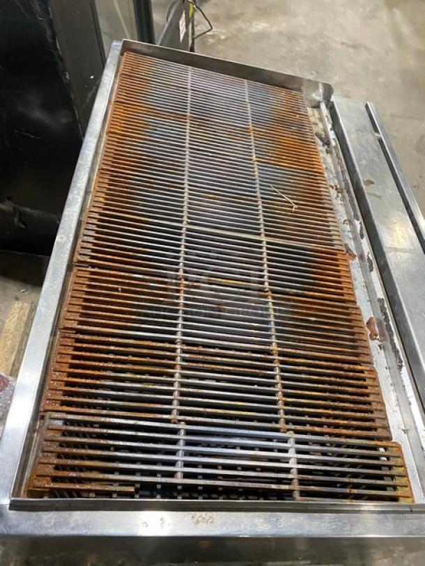 Commercial stainless steel Chitwood smoker/char broiler grill, dual-powered by natural gas/charcoal, pan slide, storage base, on casters.