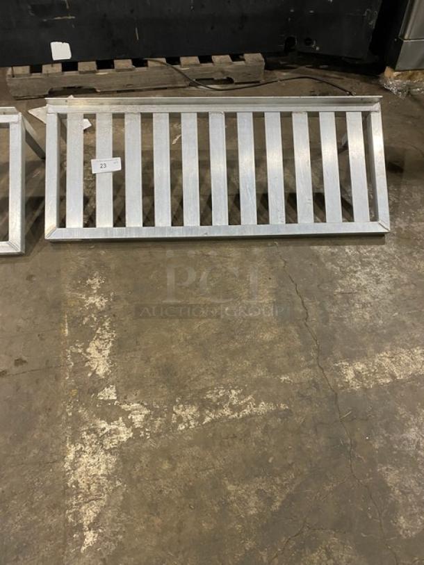 Commercial Aluminum T-Bar Wall Shelf, rectangular with metal bars, shown on a warehouse floor. Marked with tag number 23.