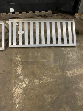 Commercial Aluminum T-Bar Wall Shelf, rectangular with metal bars, shown on a warehouse floor. Marked with tag number 23.