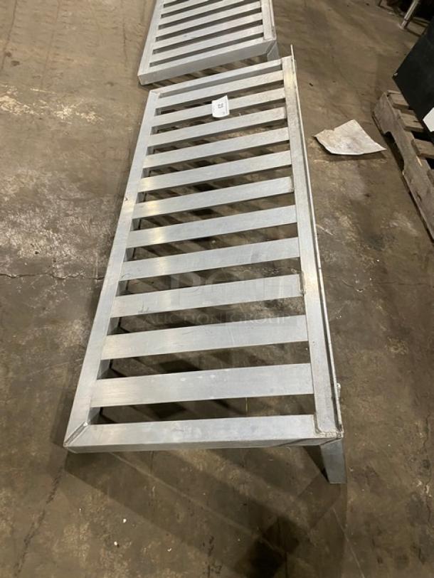 Commercial aluminum T-Bar wall shelf, slatted design, robust condition, with visible item label. Ideal for storage.