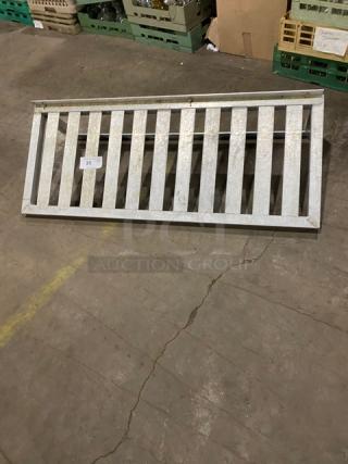 Commercial aluminum T-bar wall shelf with a slatted design, in used condition, featuring a visible label with item number 25.