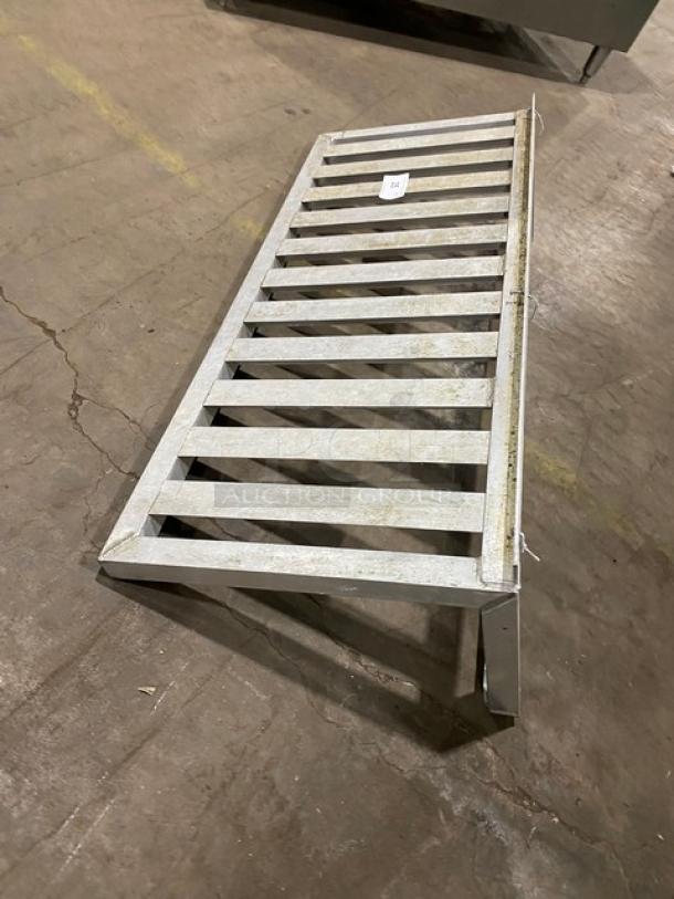 Commercial aluminum T-Bar wall shelf, features slatted design, used condition, ideal for storage, includes label with item number.