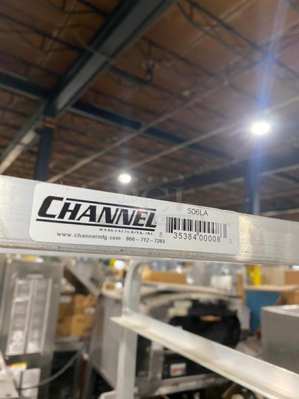 Channel Commercial Aluminum Lug/Bus Rack, Model 506LA, features casters for mobility. Label shows model and contact info.