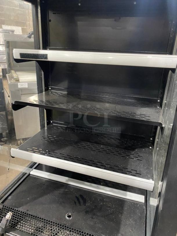 Late model black multi-tier refrigerated merchandiser display case, model 189MAC26HC, with pull-down night curtain, on casters.