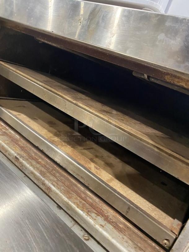 Commercial stainless steel electric countertop pizza/deck oven with thermostatic controls, showing interior racks and metal finish.