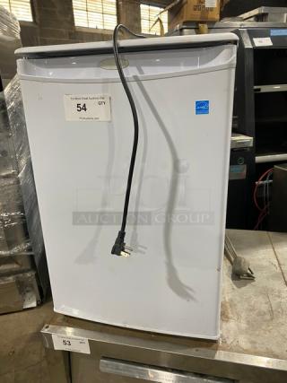 Danby Commercial white single door refrigerator, model DAR026A1WDD. Energy Star certified with poly coated wire racks. Free-standing on legs, 115V. Visible tags show auction lot number 54.
