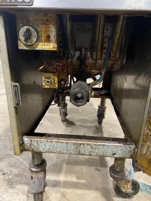 Pitco commercial stainless steel natural gas deep fat fryer with back splash, basket hanger, and casters. Shows wear.