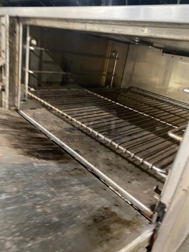 Jade Range commercial stainless steel flat top range/oven combo with wired oven rack, double overhead shelf, and on casters.