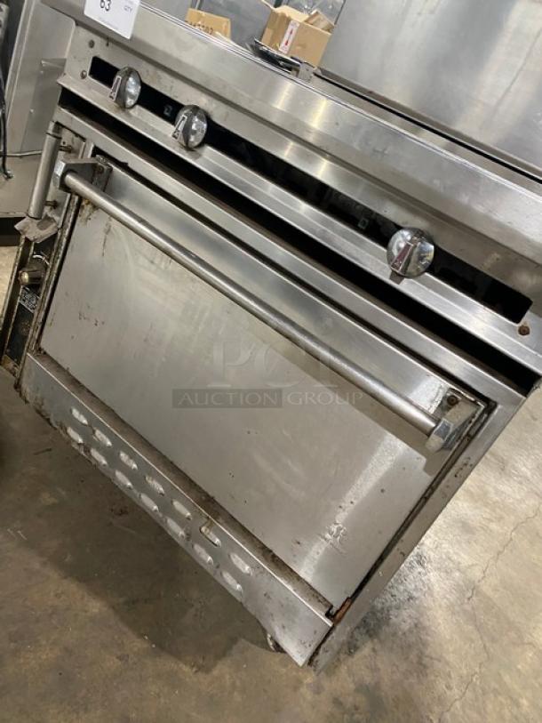 Jade Range stainless steel flat top range/oven combo with backsplash, double overhead shelf, and wired rack on casters.