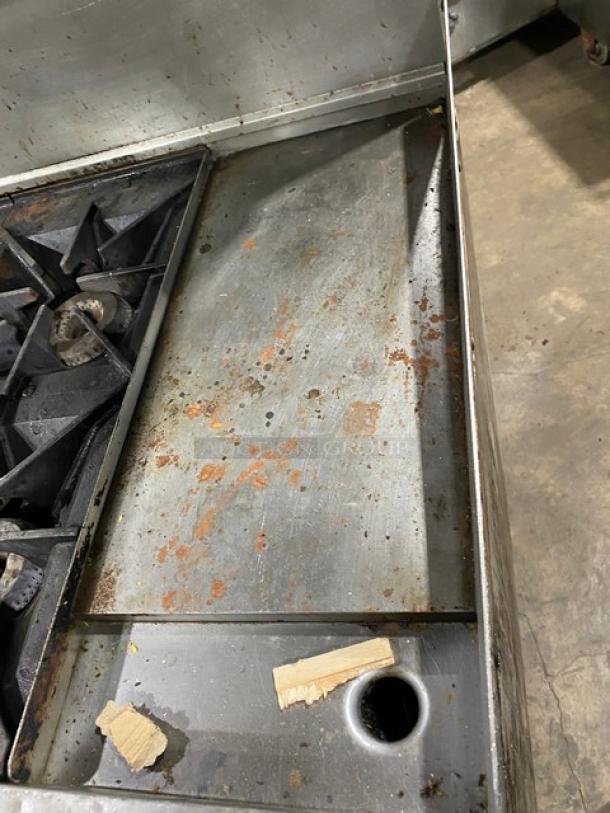 Commercial stainless steel 4-burner griddle range/oven combo with back splash, overhead salamander. Natural gas-powered, used condition.