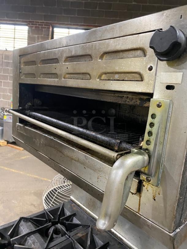 Commercial stainless steel 4-burner griddle range/oven combo with backsplash, overhead salamander broiler. Natural gas powered.