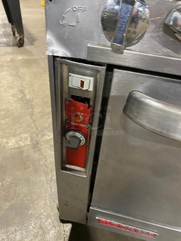 Blodgett stainless steel gas range/oven with 6 burners, backsplash, double shelf, and wired racks; on casters, with control panel.