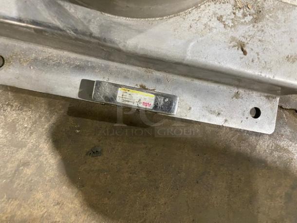 Commercial stainless steel manual mincer with black grip handle, mounted on a sturdy base. Worn label on base.