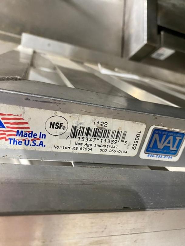 New Age Industries aluminum T-bar wall shelf, model 1122, shown. NSF label, "Made in USA" mark, and contact info visible.