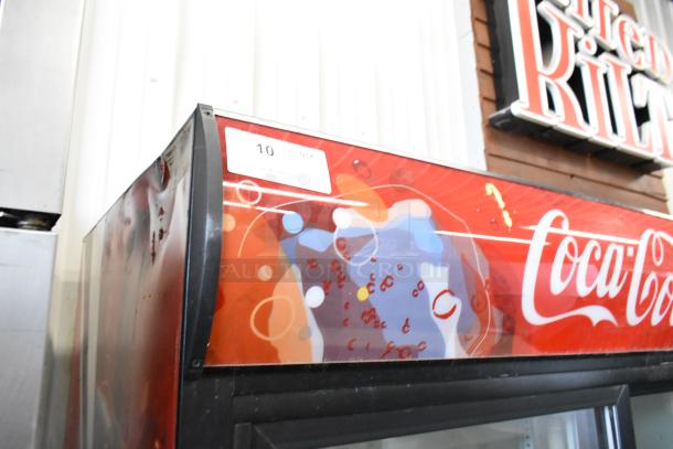 True GDM-45 metal commercial 2-door cooler merchandiser with Coca-Cola branding. Features poly-coated racks. 115 volts, 1 phase. Condition shows visible wear.