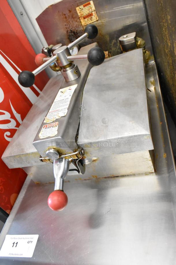 Henny Penny 600 pressure fryer, stainless steel, natural gas, 80,000 BTU, on casters, visible warning labels, light wear.