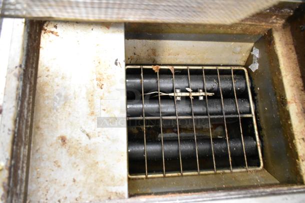 Qualite QL-9/NG commercial deep fat fryer interior with visible heating elements, metal grate, and signs of usage.