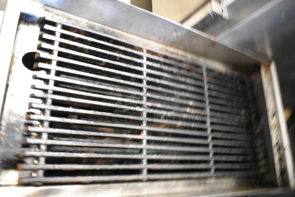 Stainless steel commercial countertop gas charbroiler grill, slightly worn, featuring sturdy grates and durable construction.