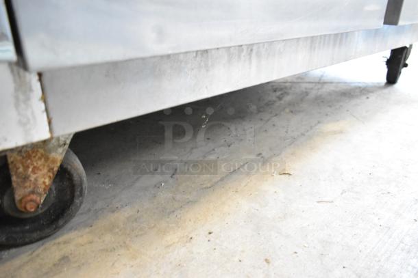 Traulsen G20010 stainless steel commercial cooler on rusted casters, view of base and floor contact.