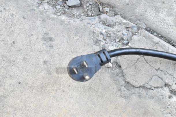 Close-up of a three-prong power plug on concrete, part of the Delfield UCD4464N-12-DD sandwich prep table.