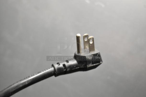 Close-up of a three-prong electrical plug, part of the Traulsen G20010 commercial cooler.