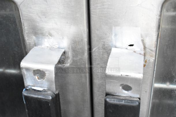Close-up of Vulcan VC4GD stainless steel oven doors with latches, showing surface scratches and metal construction.