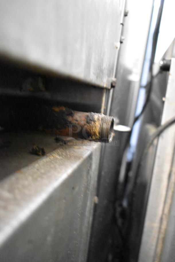A close-up view of a rusty pipe connected to a Southbend 4367A commercial gas range with visible wear.