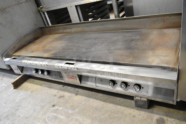 Lang stainless steel commercial countertop flat top griddle, worn surface, visible brand logos, control knobs, used condition.