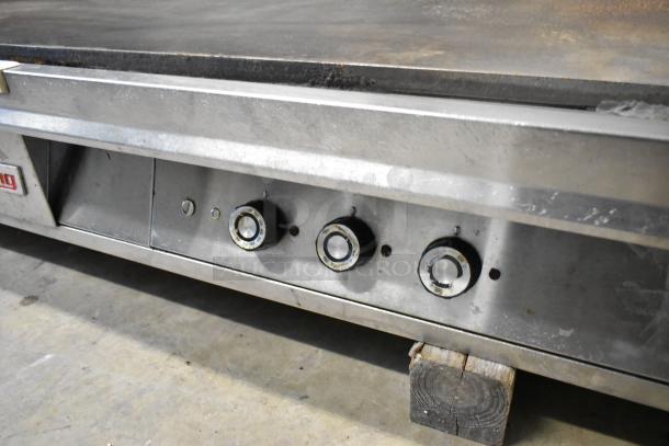 Lang stainless steel commercial countertop flat top griddle, features three adjustable knobs, visible wear, ideal for professional kitchens.