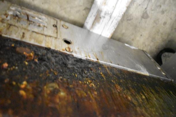 Lang stainless steel commercial flat top griddle, showing signs of heavy use with visible grease and residue on the surface.