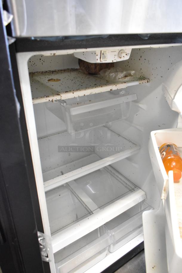 General Electric GE GTS17GSNDRSS stainless steel cooler with freezer. Interior shows signs of use; grime and food particles present.