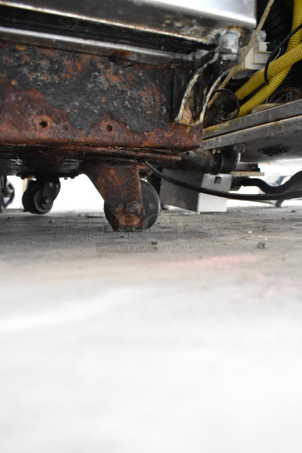 Rusty caster on a True TBB-4G-S-LD stainless steel commercial back bar cooler. Visible wear, incorrect operation may be inferred.
