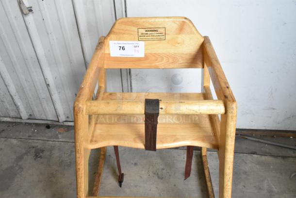 Wooden high chair with a safety strap, showing light wear. Includes a warning label and auction tag, quantity 4 chairs.