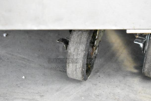 Atosa MGF8305GR stainless steel prep table on commercial casters, showing worn caster wheel detail.