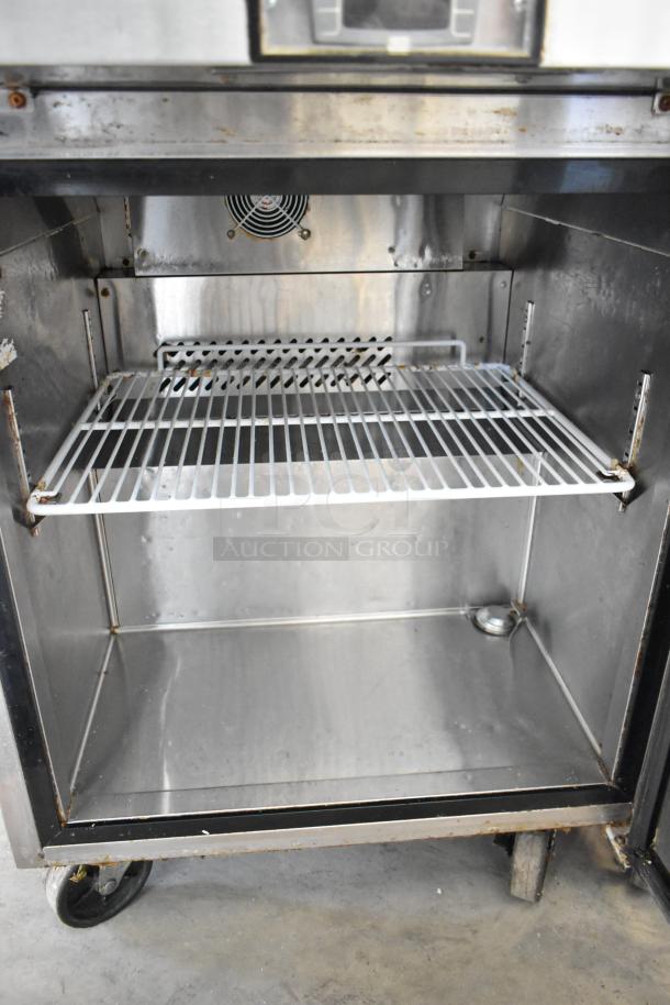 Stainless steel Atosa MGF8305GR commercial prep table, interior view. Features wire rack, fan, and commercial casters.