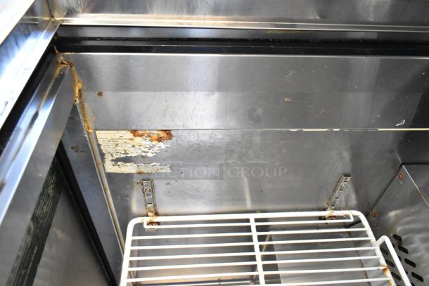 Atosa MGF8305GR stainless steel prep table interior showing rust and peeling label. Commercial casters not visible.