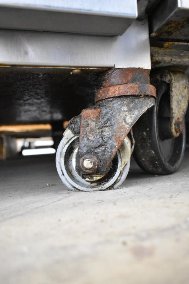 Alto Shaam 750-S heated holding cabinet caster detail, showing used condition with visible rust and wear on stainless steel.