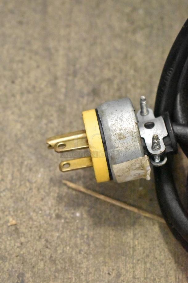 Yellow electrical plug for a True TUC-27-HC cooler, 115 volts, 1 phase, with visible metal prongs and screw attachments.