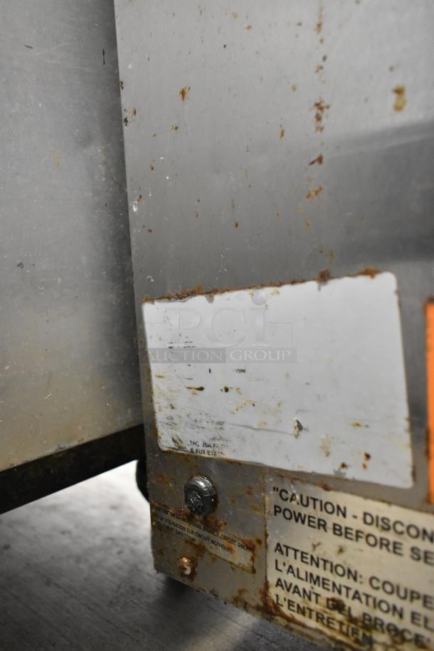 Vulcan stainless steel 3-drawer warming unit on casters, visible wear, caution and origin labels, commercial-grade.