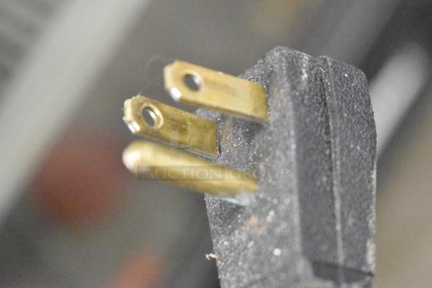 Close-up of a power plug for a True GDM-12 cooler, showing three prongs. Plug is in used condition.